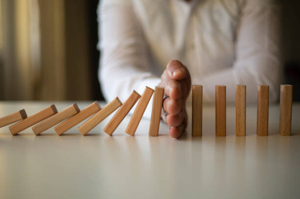 Businessman Stop Domino Effect. Operational Effectiveness Assessment - Managing Risk